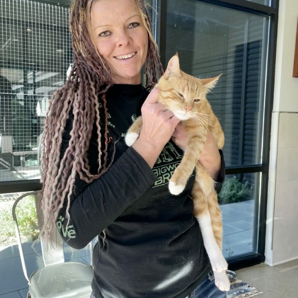 Dejia McNiel holding up an orange tabby cat in her arms